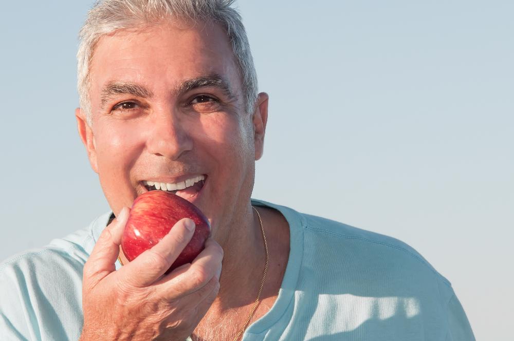 A man eating an apple after getting Modern and Affordable Dentures in Birmingham, AL